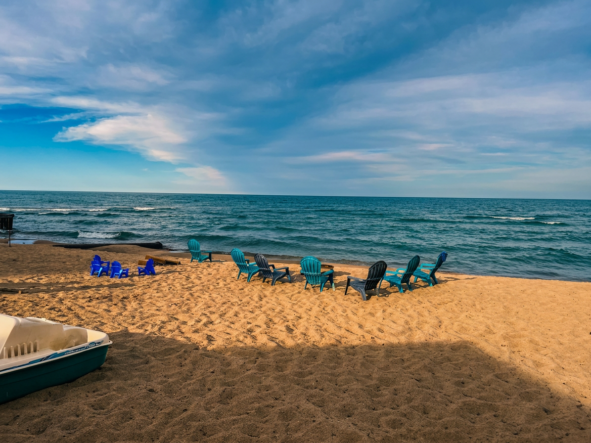 Adirondack chairs lined up on the sand at Lake Huron